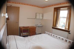 1 dormitorio con cama, escritorio y ventana en Holburn Guesthouse, en Aberdeen