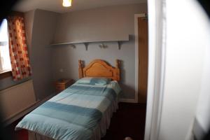 Dormitorio pequeño con cama con cabecero de madera en Holburn Guesthouse, en Aberdeen