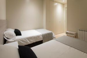 ジローナにあるBravissimo Cort Reial-2Aのベッド2台とテーブル2台が備わる小さなお部屋です。