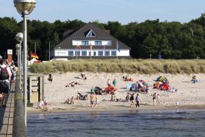 a group of people on a beach with a house at Hotel Ostseewoge in Graal-Müritz