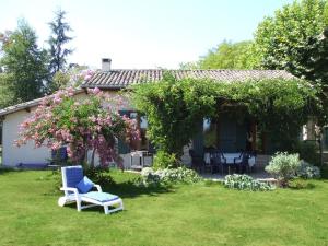 une maison avec une cour dotée d'une chaise bleue et de fleurs dans l'établissement Gites du Domaine Maison DoDo, à Lamonzie-Saint-Martin