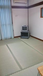 um quarto com uma televisão numa mesa e um piso em Minshuku Toshi em Yakushima