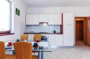 a kitchen with white cabinets and a table and chairs at Apartments Andrej in Zadar