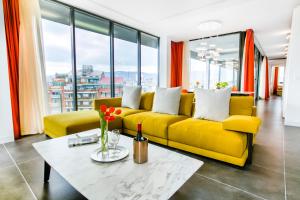 a yellow couch in a living room with windows at Cosmo Apartments Sants in Barcelona