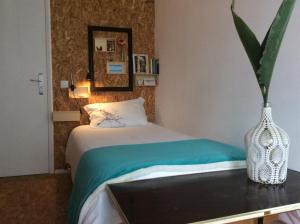 - une chambre avec un lit et un vase sur une table dans l'établissement Marina Lounge Hostel, à Ponta Delgada