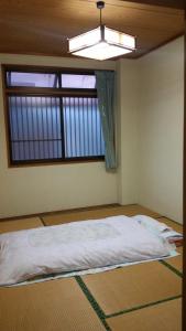 uma cama num quarto com uma janela em Minshuku Toshi em Yakushima