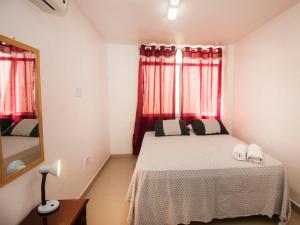Schlafzimmer mit einem Bett, einem Spiegel und roten Vorhängen in der Unterkunft El Misti Suites Copacabana in Rio de Janeiro