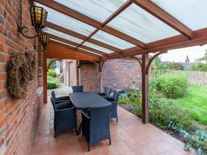 une terrasse avec une pergola en bois, une table et des chaises dans l'établissement Cozy Holiday Home in Ploegsteert with a Garden, à Le Bizet