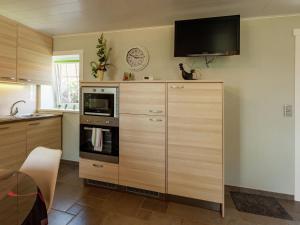 eine Küche mit einem großen Holzschrank und einer Mikrowelle in der Unterkunft Modern Holiday Home near Forest in Le Bizet in Le Bizet