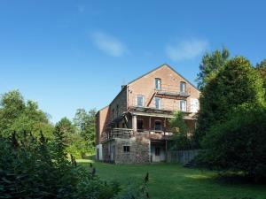 an old brick house on a lush green field at Spacious holiday home with roofed terrace in La Gleize