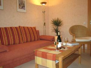 Sch ne Wohnung in der Moselregion في Kinheim: غرفة معيشة مع أريكة وطاولة مع كؤوس للنبيذ