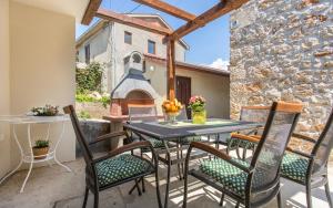 a patio with a table and chairs and a church at Apartman Bonaca in Vrbnik +33 photos