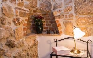 a lamp sitting on a table next to a stone wall at Apartman Bonaca in Vrbnik