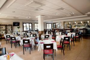 Hotel El Capricho في فيلانويفا ديل ترابوكو: غرفة طعام مع طاولات بيضاء وكراسي حمراء