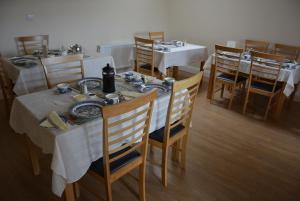 uma sala de jantar com mesas brancas e cadeiras de madeira em Copper Coast B&B em Bunmahon