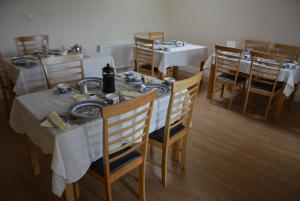 un comedor con mesas blancas y sillas de madera en Copper Coast B&B, en Bunmahon