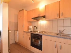 a kitchen with wooden cabinets and a sink and a stove at Captivating Apartment in Halenfeld Amel with Terrace in Amblève