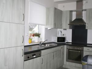 KoppにあるNice holiday home with dishwasher, in a green areaの白いキャビネット、シンク、電子レンジ付きのキッチンが備わります。