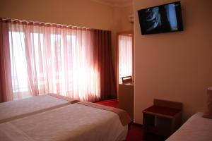 a hotel room with two beds and a tv on the wall at Hotel Quasar in Porto