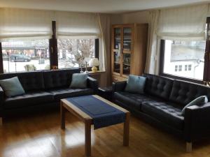 a living room with black leather couches and a table at Detached house with sauna 50m from ski lifts in Winterberg