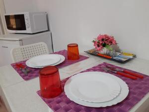 a table with two white plates on a purple table at Casa del Clown in Trapani