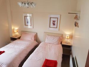 two beds in a small room with two lamps at Grant Rooms in Derry Londonderry