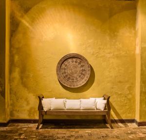 a bench in front of a yellow wall with a fan at Pousada do Ouro in Paraty