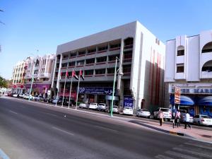 een stadsstraat met auto's die voor een gebouw geparkeerd staan bij Top Hotel Apartments in Al Ain