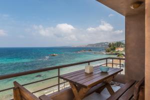 a wooden table on a balcony overlooking the ocean at Nais Apartments & Studios in Chania