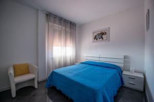 a white bedroom with a blue bed and a chair at Casa Elite in Bardolino