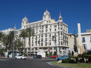a large white building with cars parked in front of it at Apartamentos Romero in Alicante