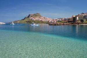 a small boat in a body of water with a city at Best Western Hotel Blumarea in Castelsardo