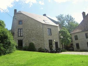 ein altes Steinhaus mit zwei Tischen und Stühlen im Hof in der Unterkunft Lively Holiday Home in Viroinvlal with Garden in Treignes