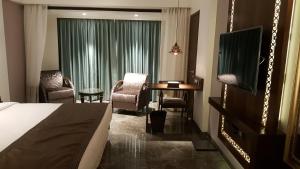 a hotel room with a bed and a desk and a television at Peninsula Redpine-Airport in Mumbai
