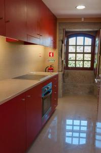 a kitchen with red cabinets and a sink and a window at Casa da Torre in Sobrosa