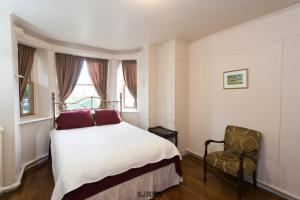 a bedroom with a bed and a chair and a window at A Tanners Home Inn Bed and Breakfast in Saint John