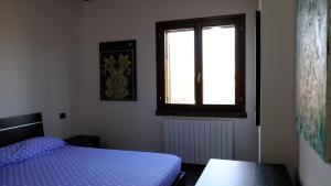 sypialnia z niebieskim łóżkiem i oknem w obiekcie La Baia Casa Vacanze w mieście Portoscuso