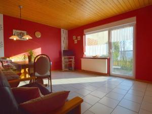 a living room with red walls and a large window at Apartment in M rsdorf with terrace in Mörsdorf