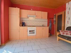 a kitchen with orange walls and a white tile floor at Apartment in M rsdorf with terrace in Mörsdorf