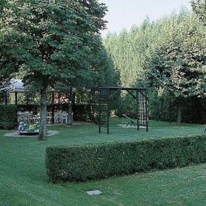a playground in a park with a tree and a swing at Hotel La Corte in Rubiera