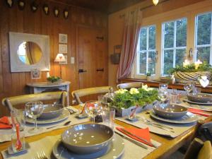 ein Esszimmer mit einem Tisch mit Tellern und Gläsern in der Unterkunft Spacious Chalet with Private Garden in Waimes in Sourbrodt