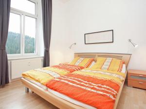 a bedroom with a bed with orange and yellow blankets at Moderne Villa in Borstendorf mit Park in Leubsdorf