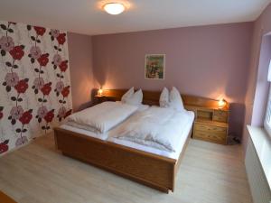 a bedroom with a large bed with white sheets at Holiday home in Densborn with garden in Zendscheid