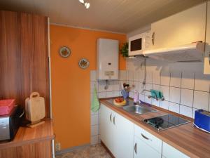 una piccola cucina con pareti arancioni e lavandino di Holiday home in Thuringia a Neuhaus am Rennweg