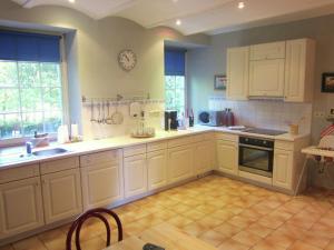 una cocina con armarios blancos y un reloj en la pared en Welcoming Cottage in Offagne with Garden, en Offagne