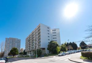 a tall white building with cars parked in a parking lot at LovelyStay - Casas Brancas - Modern Apartment with Balcony & free private parking in Porto