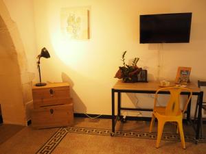 einen Schreibtisch mit einem TV und einem Schreibtisch mit einem Stuhl in der Unterkunft L'altro capo del filo in Syrakus