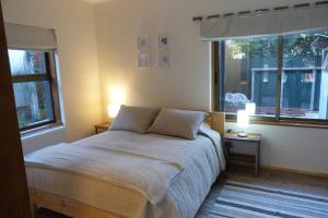 a bedroom with a large bed with two windows at Edificio Guadalauquen in Valdivia