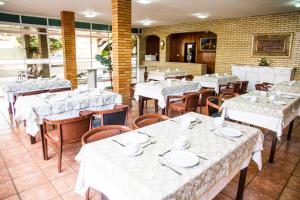 a restaurant with tables and chairs with white tablecloths at Hotel Barrocos in Goiatuba