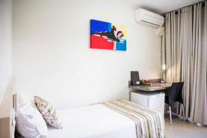 um quarto com uma cama e uma secretária com um computador em Hotel Barrocos em Goiatuba